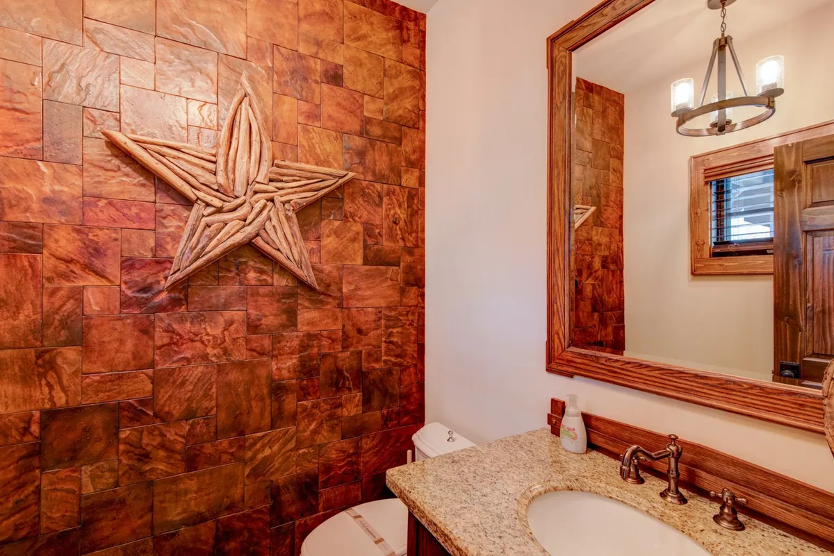A charming bathroom with a granite countertop, starfish wall decor, and a wooden mirror frame. The soft lighting and decorative accents create a welcoming, homey feel—ideal for a convenient half bath experience.