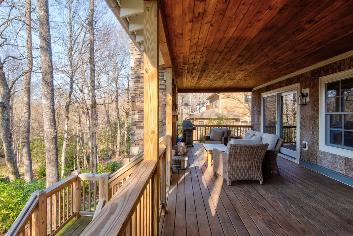 This image features a wooden deck with comfortable outdoor seating and a grill, set against a backdrop of natural surroundings. The scene suggests a peaceful retreat where guests can enjoy being immersed in the outdoors, with opportunities for relaxation, entertaining, or simply taking in the views.
